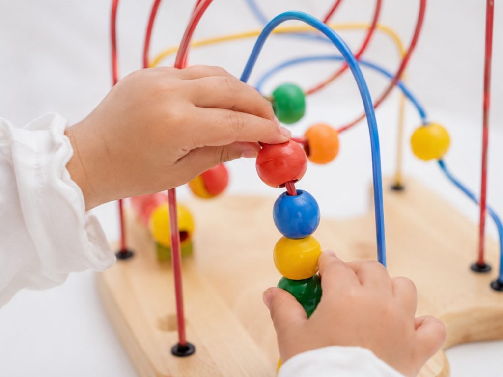Close-up of a child using a wooden maze toy to improve fine motor skills and hand-eye coordination.