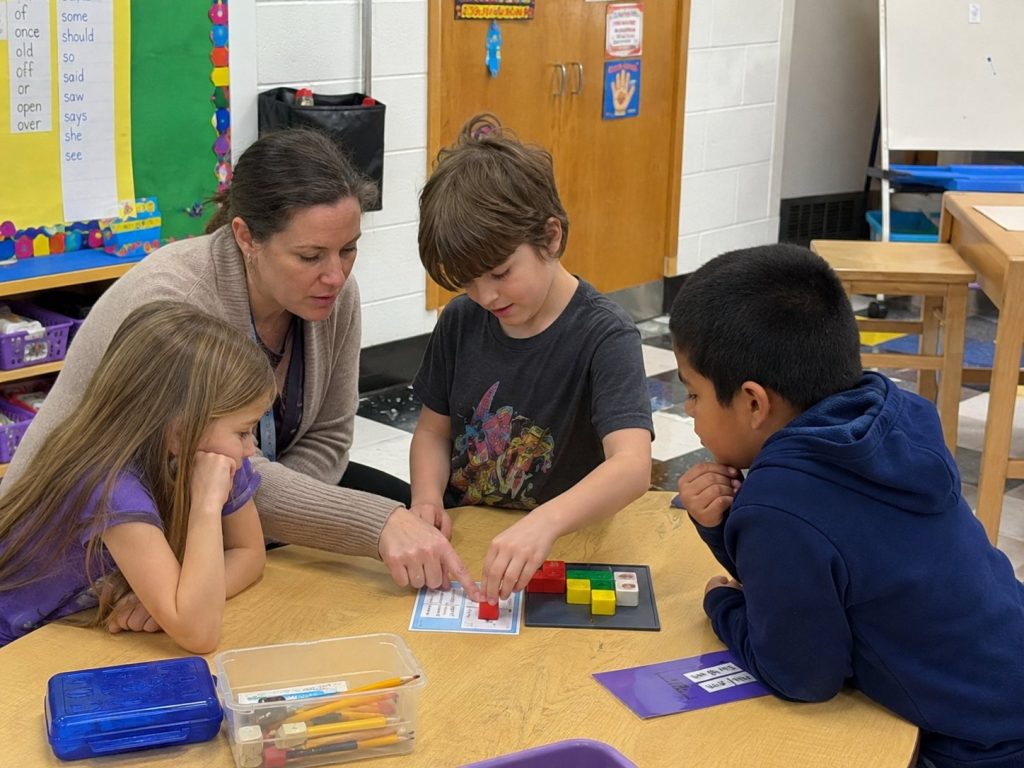 A teacher guiding students through a logic toy activity during a classroom rotation.